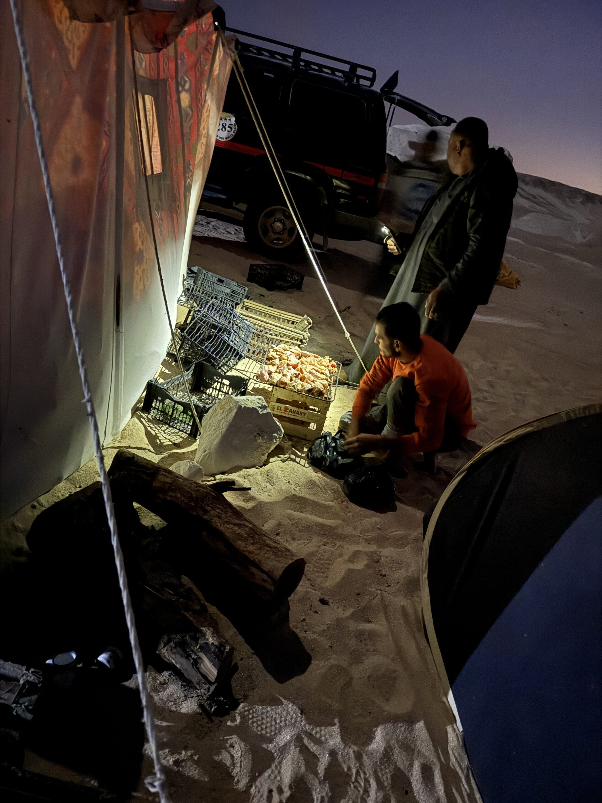 暗くなったキャンプ地でガイドが夕食を準備する様子